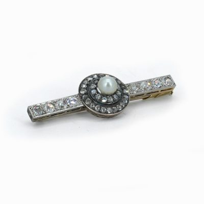 Broche ancienne en platine sertie d'une perle fine naturelle entourée de diamants taille ancienne.